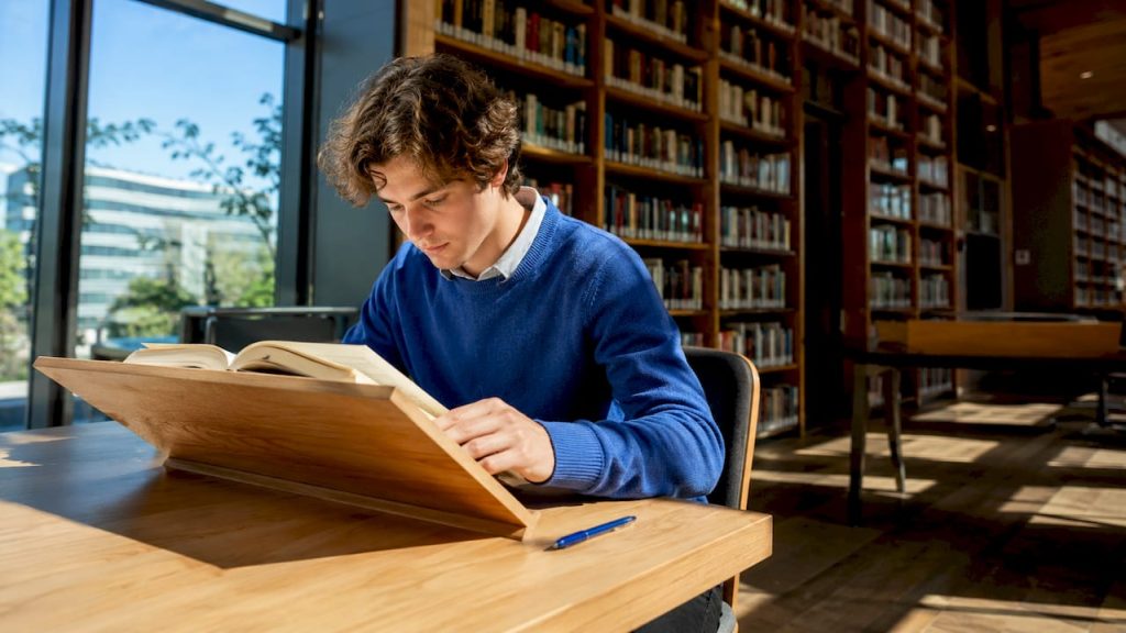 Aan de eettafel zit iemand rustig een Spaans boek te lezen.