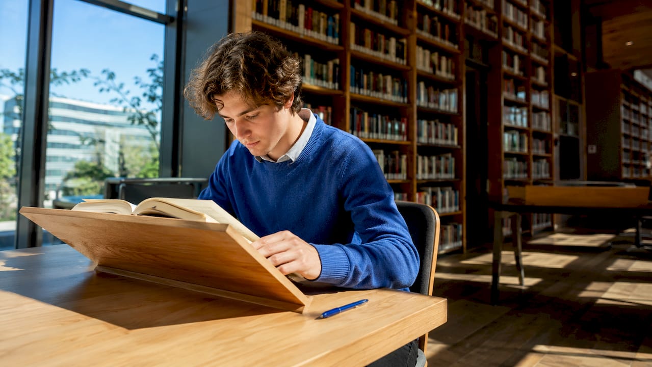 Aan de eettafel zit iemand rustig een Spaans boek te lezen.