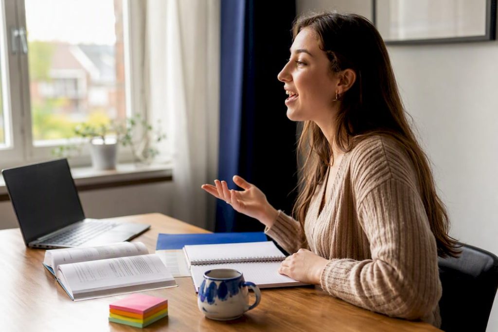 Persoon spreekt Nederlands aan een bureau thuis